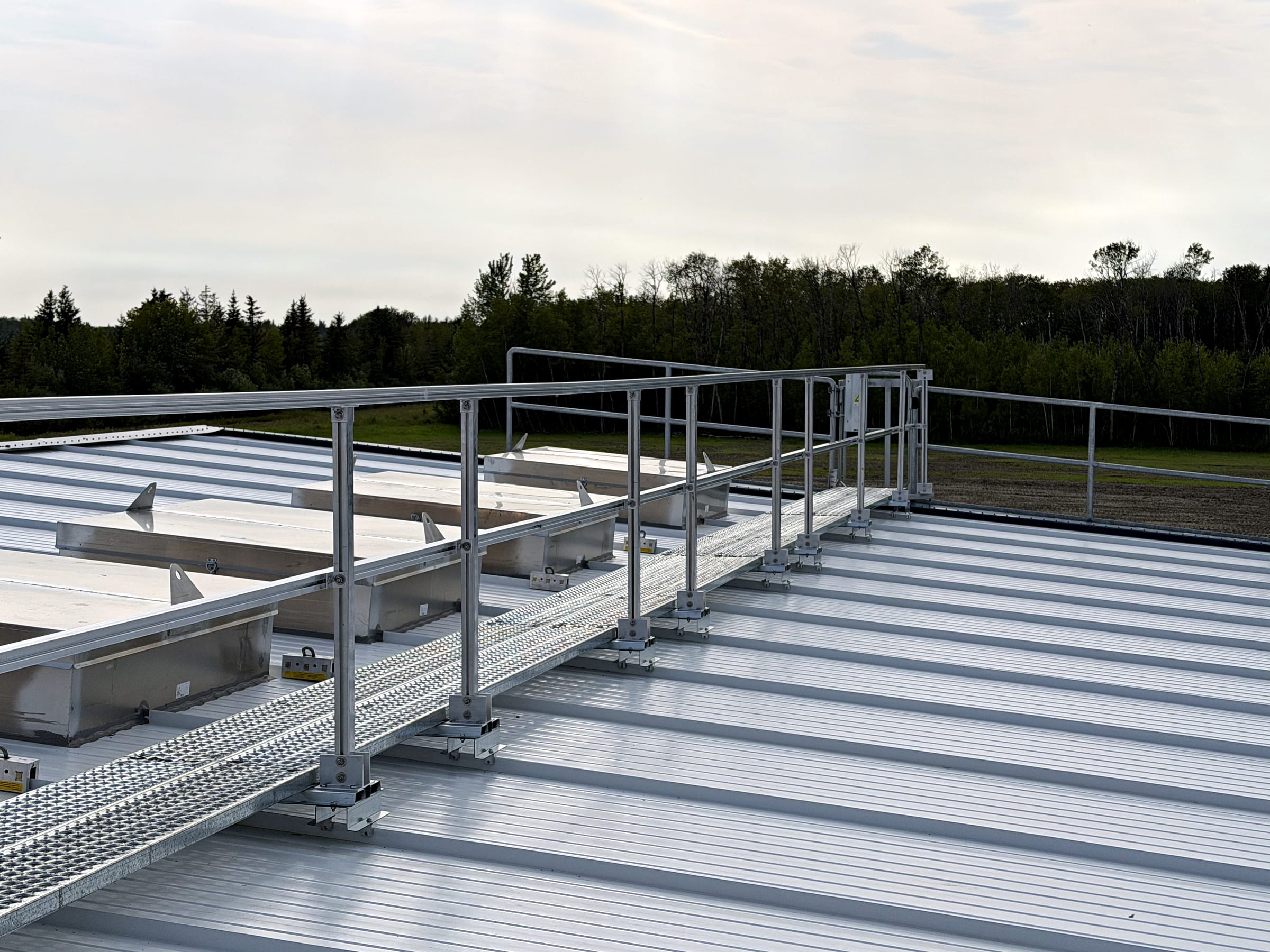 Diagonal walkway and guardrail crossing a white standing-seam roof.
