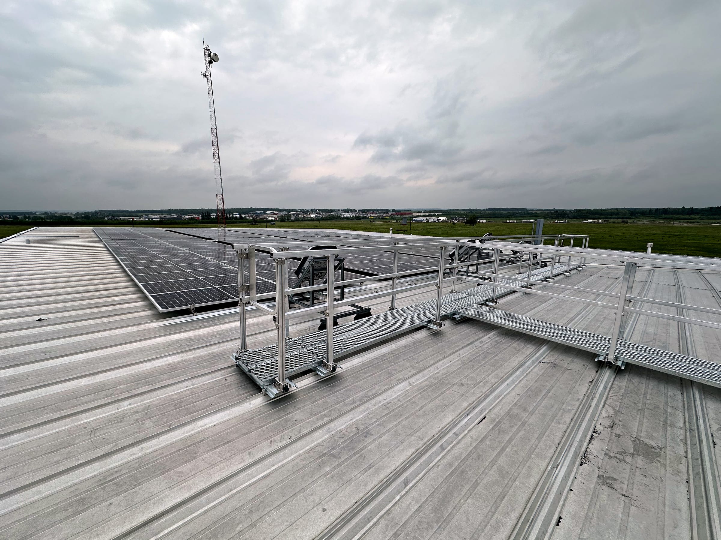 Elevated guardrail walkway beside a solar panel array.
