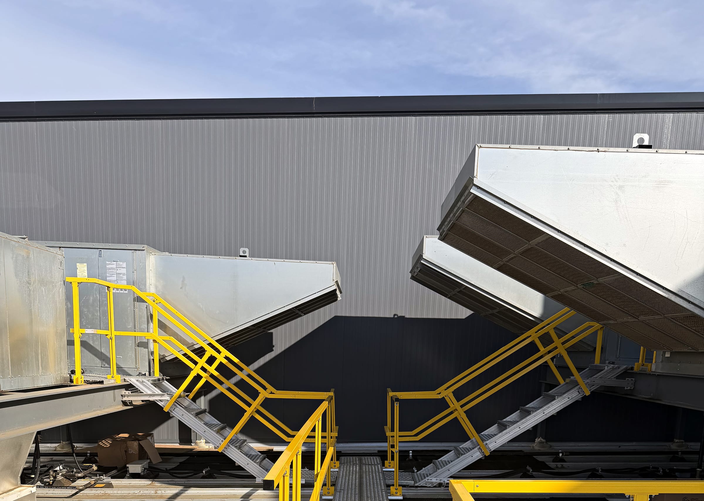 Two safety-yellow crossover staircases leading to rooftop equipment.